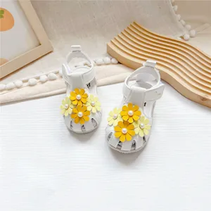 Detailansicht weißer Baby-Ledersandalen mit gelben Blumen und Perlenakzenten.