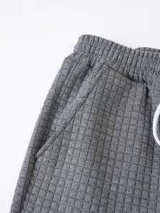 Close-up detail of grey grid textured fabric and waistband of men's casual shorts