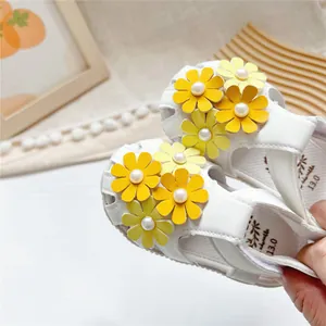 Detailansicht weißer Kleinkindsandalen mit gelben Blumenanhängern und Perlenmitte