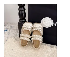 Gros plan de chaussures plates dorées pour filles avec perles et nœuds décoratifs