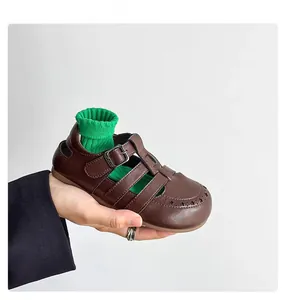 Detail shot of retro brown leather kids' sandal with star cutouts and buckle.