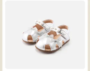 Nahaufnahme silberner Babysandalen für Mädchen mit weißer Schleife und elegantem Perlenband