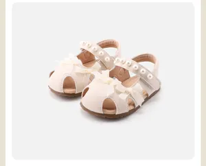 Detailansicht der cremefarbenen Babyschuhe mit weißen Schleifen und Perlen verzierten Riemen
