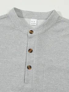 Detailed view of a gray waffle knit Henley shirt collar featuring tortoiseshell buttons