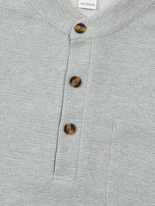 Close-up macro view of men's grey waffle knit Henley shirt showing texture and buttons