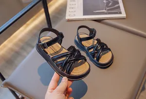 Détail de sandales romaines noires pour filles avec brides croisées et semelle souple.