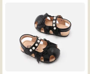 Detailansicht der schwarzen Baby-Sandalen für Mädchen mit Schleifen und Perlenriemen