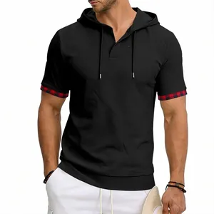 Détail d'un t-shirt à capuche noir pour homme avec revers de manches à carreaux rouge.