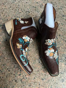 Vista detallada de botines camperos marrones bordados con flores y tacón grueso.