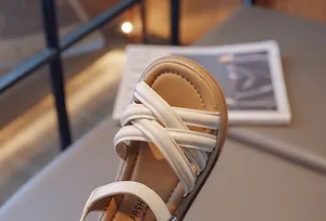 Gros plan sur les sandales romaines blanches pour filles avec un design croisé