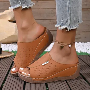 Close-up of tan wedge sandals featuring laser-cut floral patterns and a FASHION label.