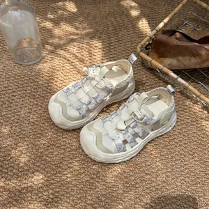 Detail of breathable mesh children's sandals with closed-toe design on a textured rug.
