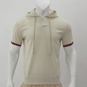Détail montrant le tissu gaufré et le revers à carreaux du t-shirt à capuche beige.