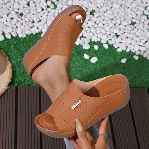 Detailed view of brown wedge sandals featuring intricate laser-cut floral patterns