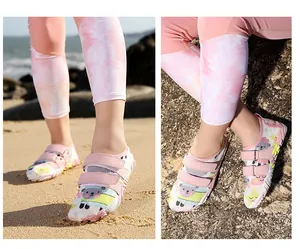Rosa Kinder-Wasserschuhe mit Schafmuster auf dem Sandstrand und Felsen gezeigt