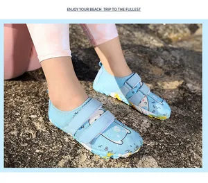 Nahaufnahme von blauen Badeschuhen für Kinder mit süßen Cartoon-Motiven auf Strandfelsen