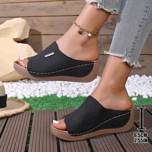 Close-up showing the laser-cut floral detail on these stylish black wedge slippers.