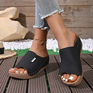 Close-up of black wedge slippers with laser-cut floral patterns and thick soles