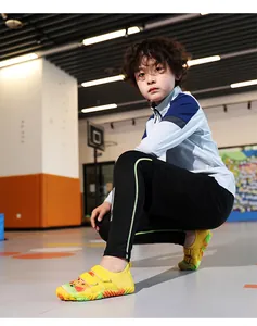 Junge trägt gelbe Cartoon-Wasserschuhe in einer hellen Indoor-Sporthallen-Umgebung.