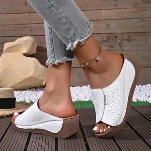 Close-up of white wedge sandals with laser-cut star patterns on wooden deck.