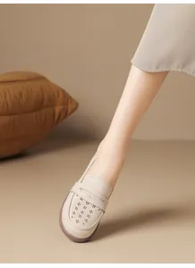 Close-up macro detail of beige hollow-out soft leather loafers worn comfortably on foot