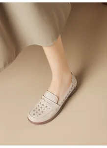 Close-up of beige soft leather loafer with elegant hollowed-out floral pattern details