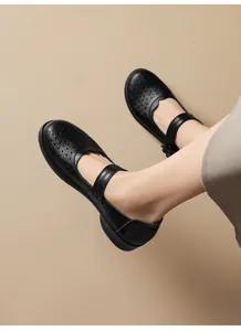Close-up view of black leather hollow-out Mary Jane flats with ankle strap