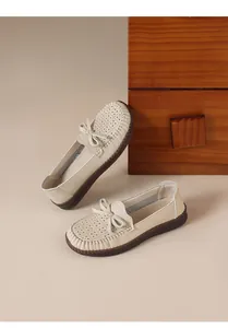 Nahaufnahme bequemer beigefarbener Leder-Loafers mit Lochmuster und Schleifendekoration