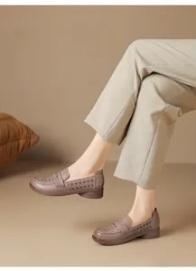 Close-up of brown perforated soft leather loafers worn by a model in a studio