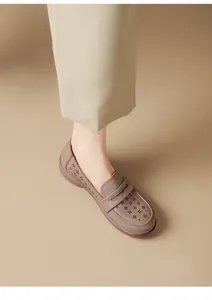 Detailed shot of brown soft leather loafer with hollow-out floral design and flat sole.