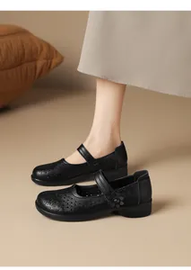 Close-up detail of vintage black breathable perforated Mary Jane shoes with floral accents.