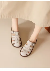 Close-up view of beige woven leather sandals with adjustable buckle on model's feet