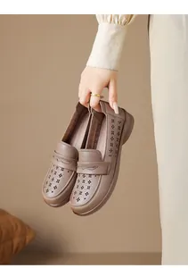 Detail view of stylish brown leather loafers with floral laser cutouts held by hand
