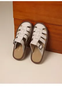 Macro view of woven leather texture on these retro cream ladies slides with side buckles