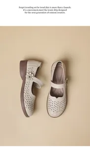 Detail of beige laser-cut Mary Jane shoes with soft sole and floral buckle detail.