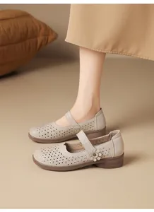 Close-up detail of beige leather hollowed-out Mary Jane shoes with floral accent