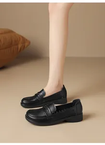 Elegant black soft leather loafers featuring hollow patterns shown on model foot and floor.