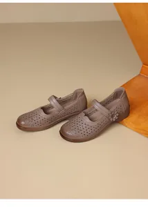 Detailed view of brown laser-cut leather flat shoes featuring an elegant side flower decor
