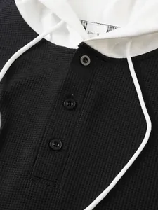 Detailed view of men's waffle knit hooded t-shirt with black buttons and texture