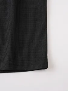 Close-up of black waffle knit fabric and stitched hem on men's casual short sleeve T-shirt