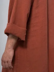 Close-up of terracotta linen-textured long sleeve with rolled cuff for men's retro robe.