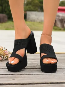 Dettaglio di sandali platform in maglia nera con tacchi alti spessi su pedana in legno
