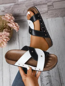 Close-up of women's black and white cross-strap sandals with decorative rivets