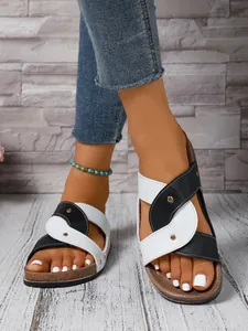 Detailed view of fashionable black and white studded crossover strap sandals on model's feet