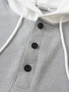 Macro detail showing waffle texture fabric and black buttons on men's hooded T-shirt