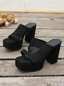 Dettaglio ravvicinato di eleganti sabot platform in maglia nera con tacco alto largo