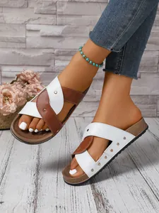 Detail view of women's cross-strap sandals with rivets on a summer-themed background