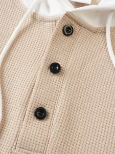 Close-up of men's waffle knit hoodie showing black button details and fabric texture
