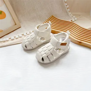Detail view of off-white closed-toe kids leather sandals with adjustable velcro straps