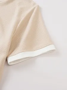 Macro view showing the soft waffle knit fabric and white contrast cuff of a men's t-shirt.